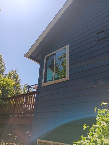 White slider on a dark blue house beside a wood deck