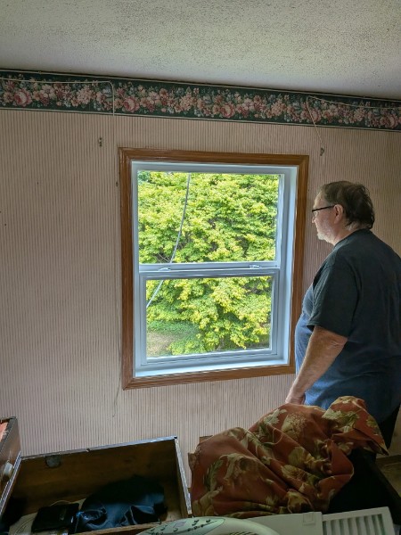 Homeowner standing beside a new white double-hung set in existing wood trim