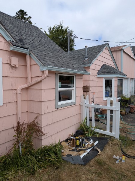Pink bungalow with new white double-hung windows after replacement