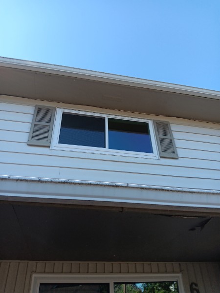 White slider window with shutters above a porch