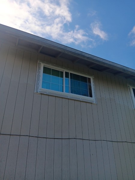Close view of an upper-story white slider on tan vertical siding