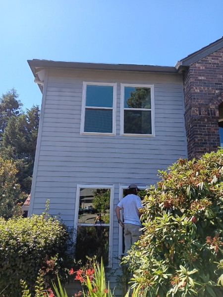 Stacked white vinyl windows on a two-story light siding house